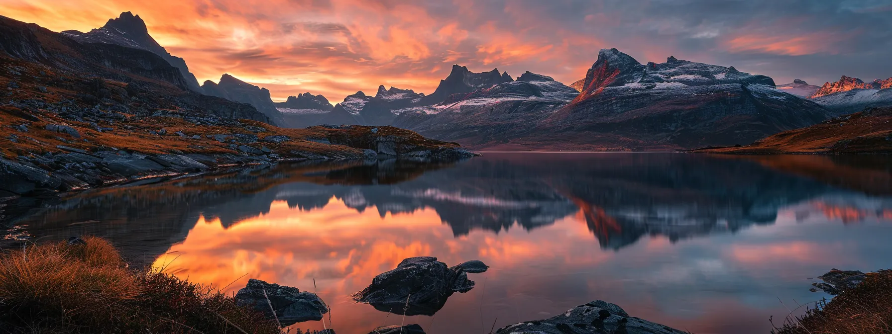 a breathtaking landscape at sunrise, with vibrant orange and pink hues illuminating the rugged mountains and a serene, reflective lake below, encapsulating the tranquility of nature's beauty.