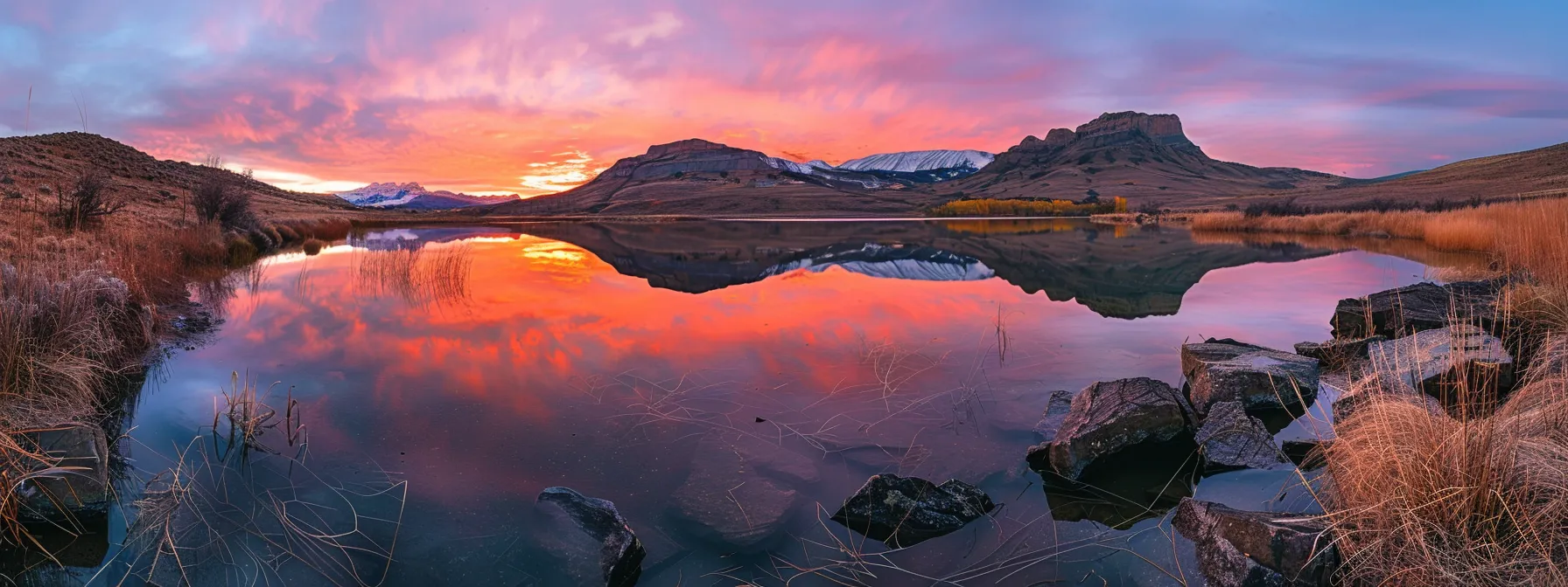 a breathtaking sunrise casts golden hues over a tranquil mountain lake, reflecting the vibrant colors of the sky in its crystal-clear waters, creating an enchanting and serene landscape.