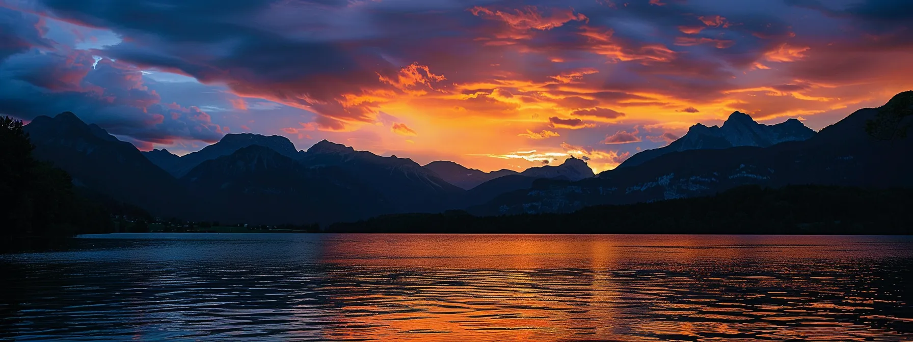 a breathtaking sunset casts a golden glow across a tranquil lake, where the silhouettes of majestic mountains rise sharply against the colorful sky, creating a serene and captivating atmosphere.