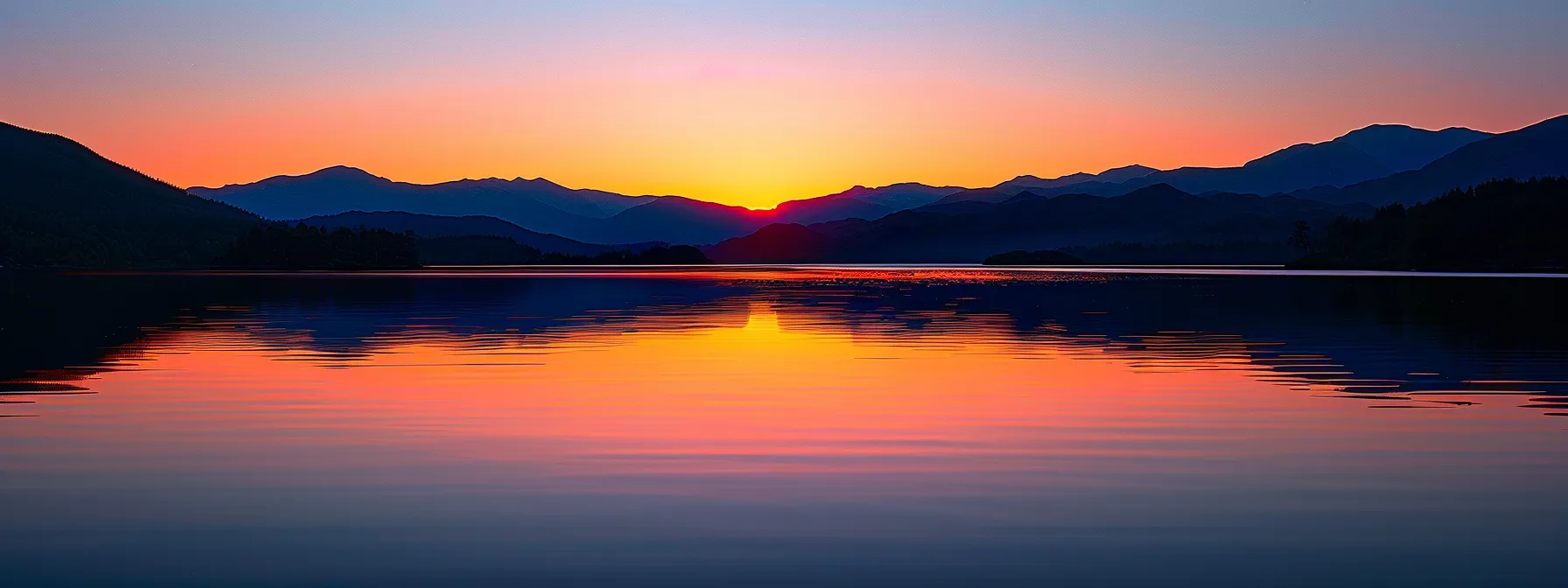 a breathtaking sunset casts vibrant hues of orange and pink across a tranquil lake, reflecting the majestic silhouette of distant mountains under a clear sky.