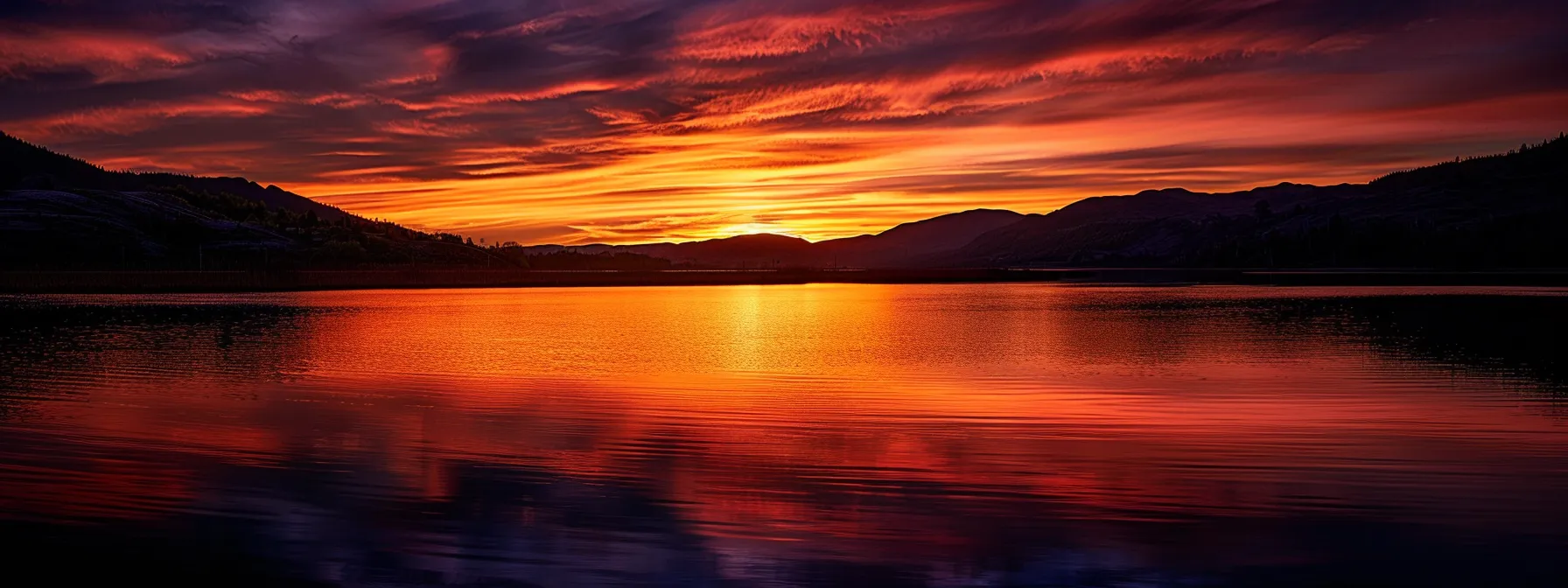 a breathtaking sunset casts vibrant hues of orange and purple over a tranquil lake, reflecting the dramatic sky while silhouettes of distant mountains create a serene backdrop.