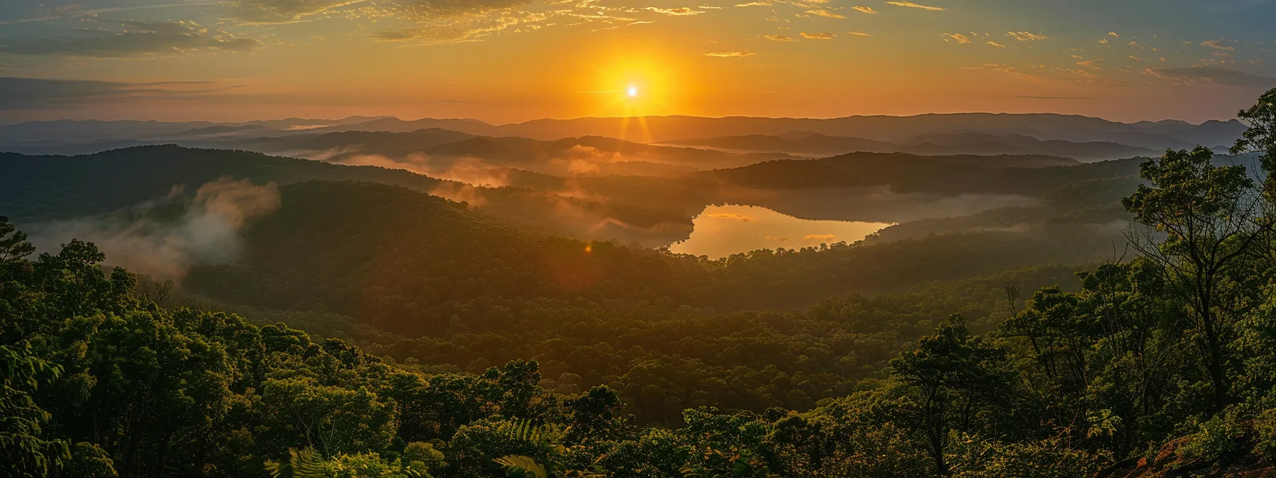 a majestic sunrise casts golden light over a serene mountain landscape, where mist gently blankets the valleys and a tranquil lake reflects the vibrant hues of dawn.