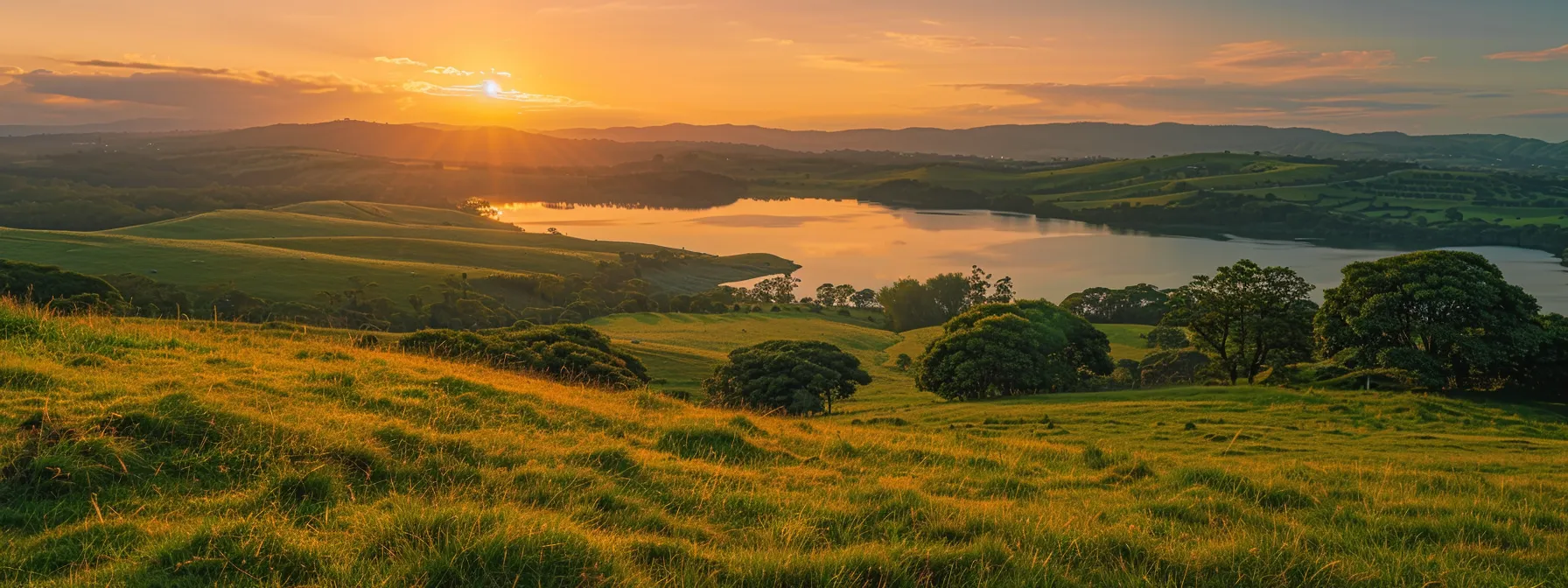 a serene landscape captures the breathtaking beauty of a golden sunrise illuminating a tranquil lake, surrounded by lush green hills and a vibrant sky painted in shades of orange and pink.