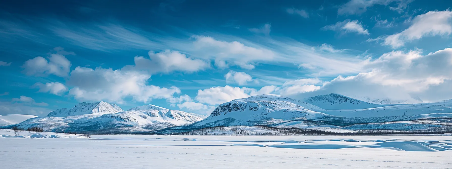 a serene winter landscape unfolds, showcasing a majestic snow-covered mountain range under a vivid azure sky, with soft, billowing clouds accentuating the crispness of the chilly air.