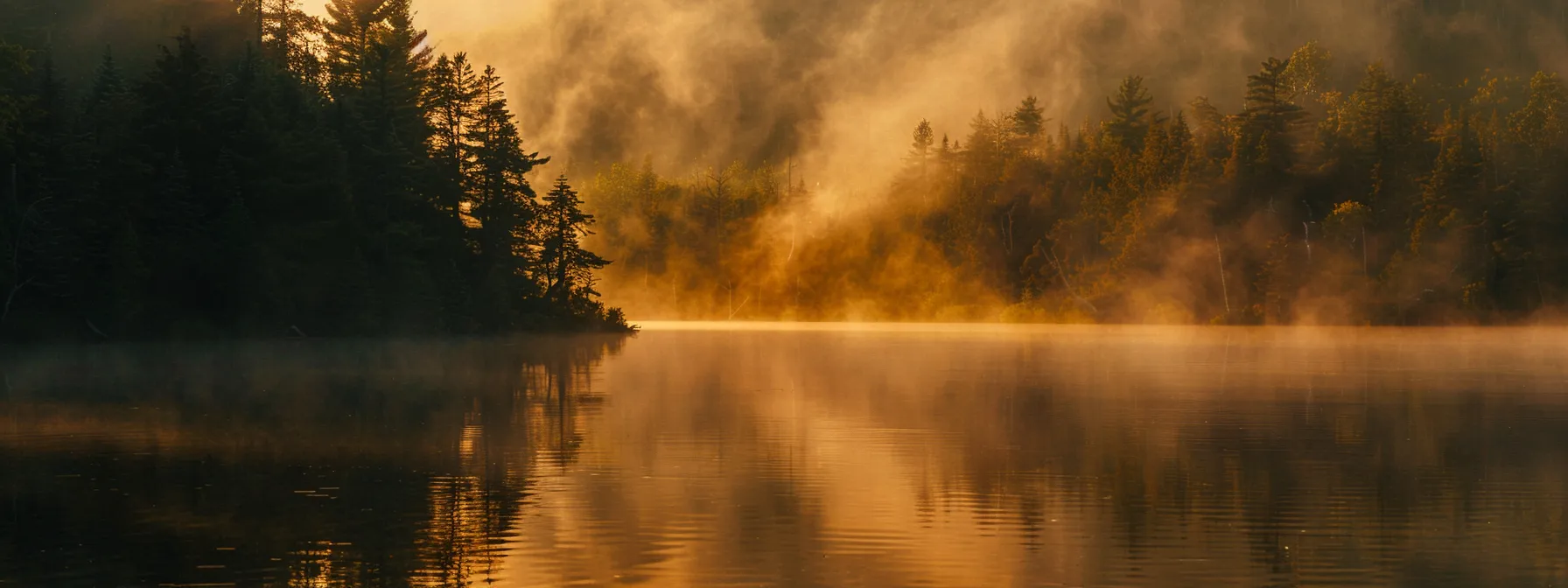 a vibrant sunrise casts a golden glow over a tranquil lake, where mist gently rises from the water's surface, reflecting the colorful sky and creating an idyllic atmosphere.