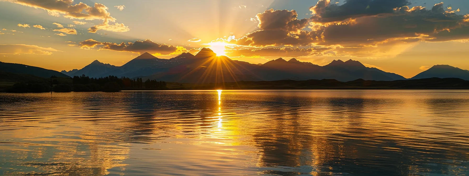 a vibrant sunset casts a golden glow over a tranquil lake, where the silhouette of majestic mountains reflects beautifully on the water's surface, creating a serene and captivating atmosphere.