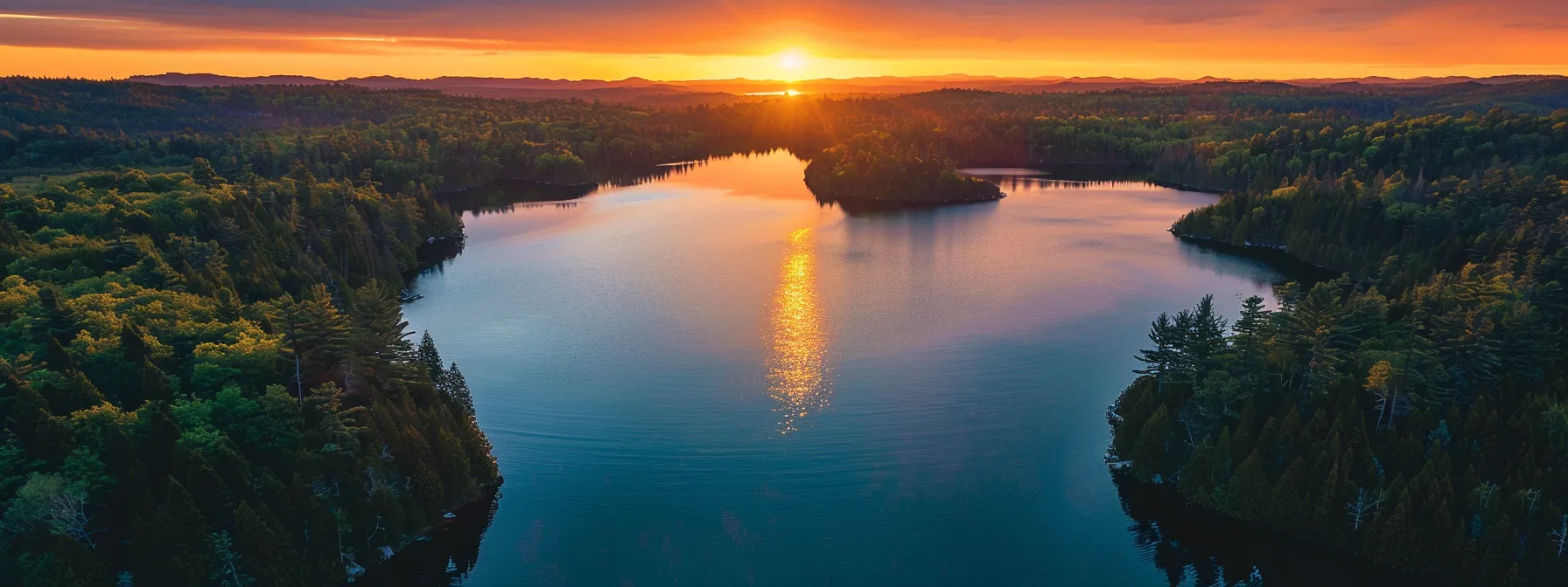 a vibrant sunset casts a warm golden glow over a tranquil lake, reflecting the vivid colors of the sky and surrounded by lush, emerald green trees.