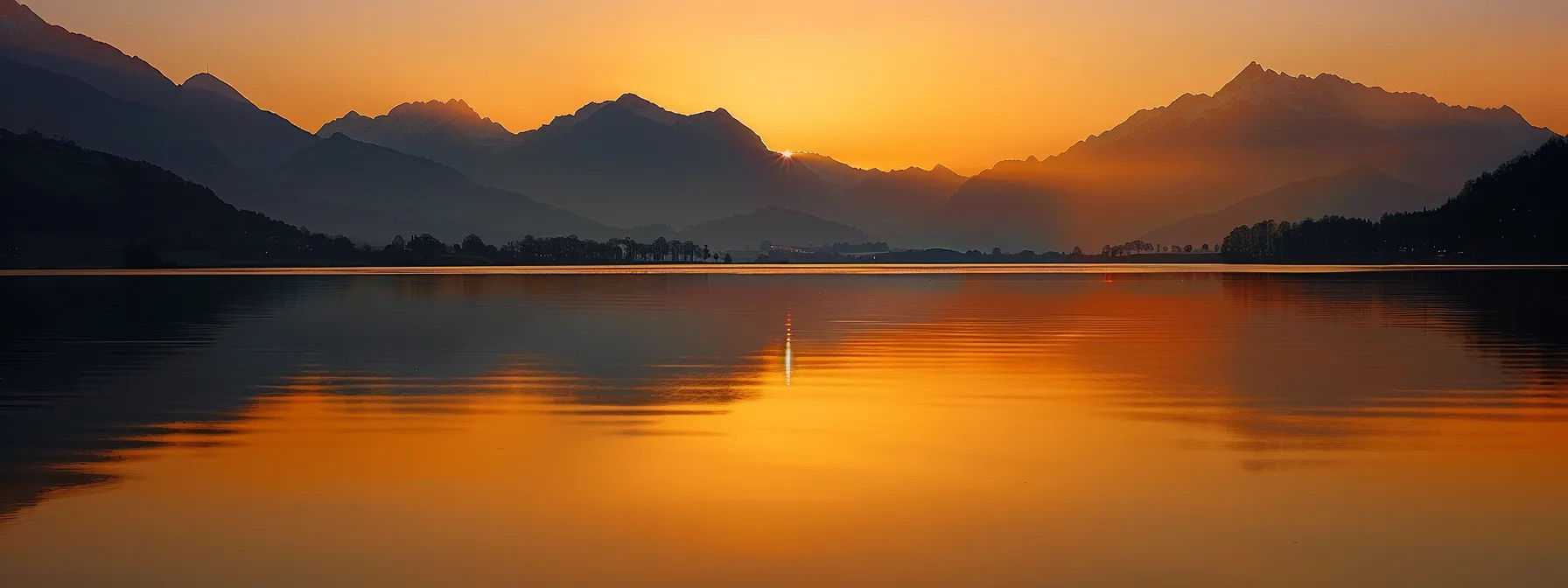 a vibrant sunset casts a warm golden glow over a serene lake, reflecting the silhouettes of majestic mountains in the distance, creating a tranquil and awe-inspiring atmosphere.