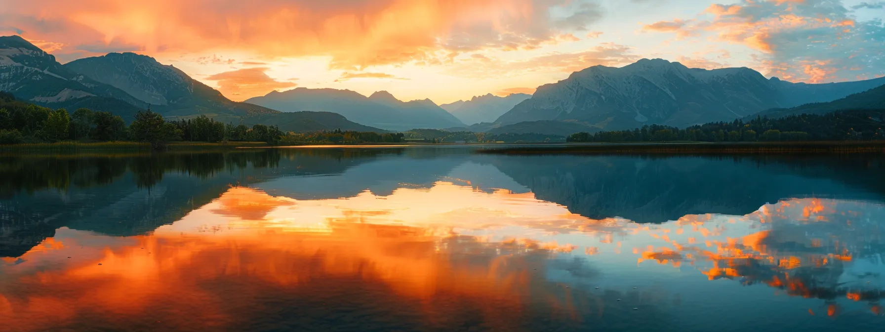 a vibrant sunset casts warm golden hues over a tranquil lake, where majestic mountains reflect in the shimmering water, creating a serene and picturesque landscape.