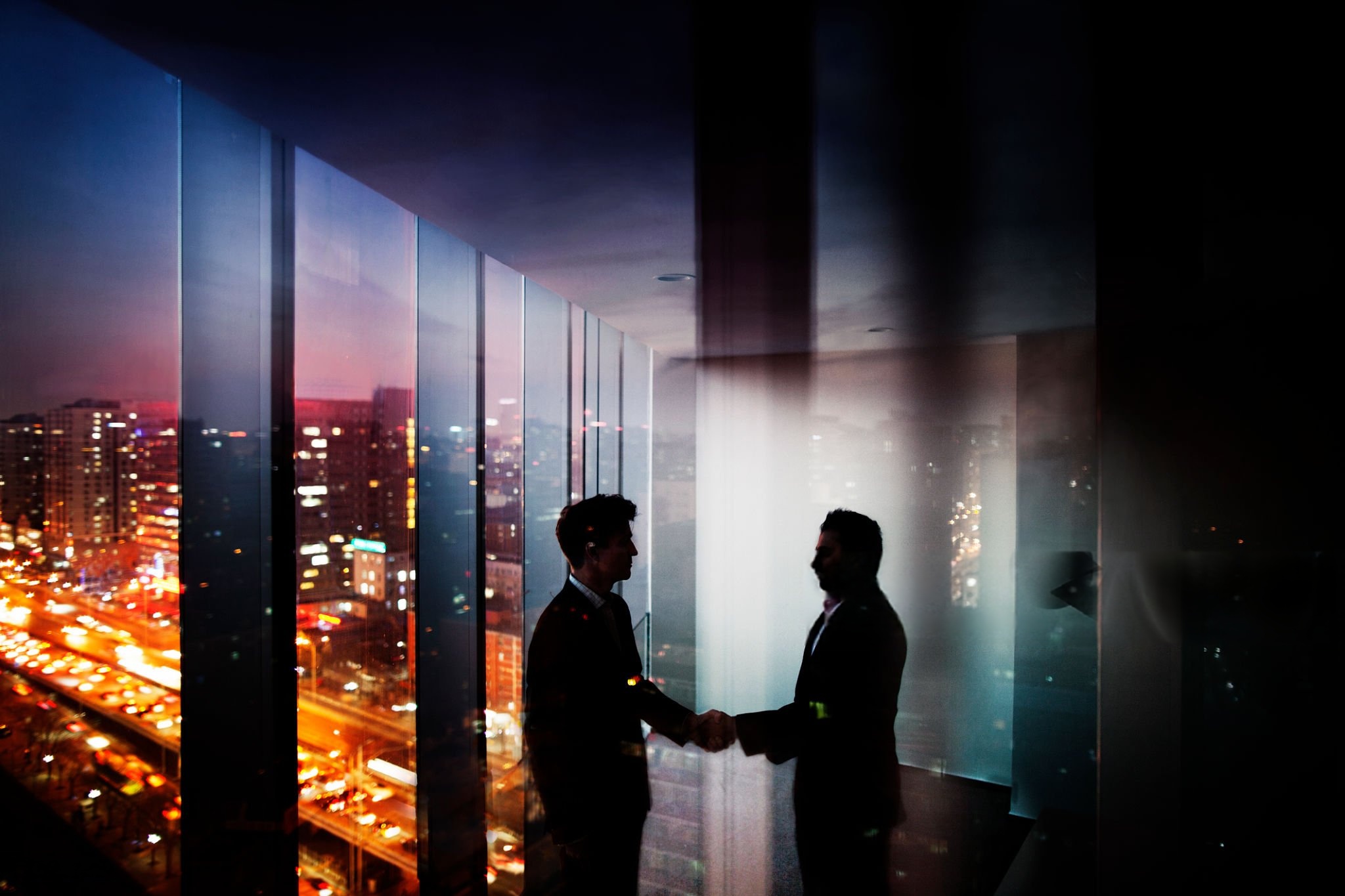 Business deal sealed with a handshake against a city skyline at dusk